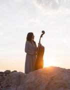 female-musician-with-cello-outdoors-sunset_23-2148737116